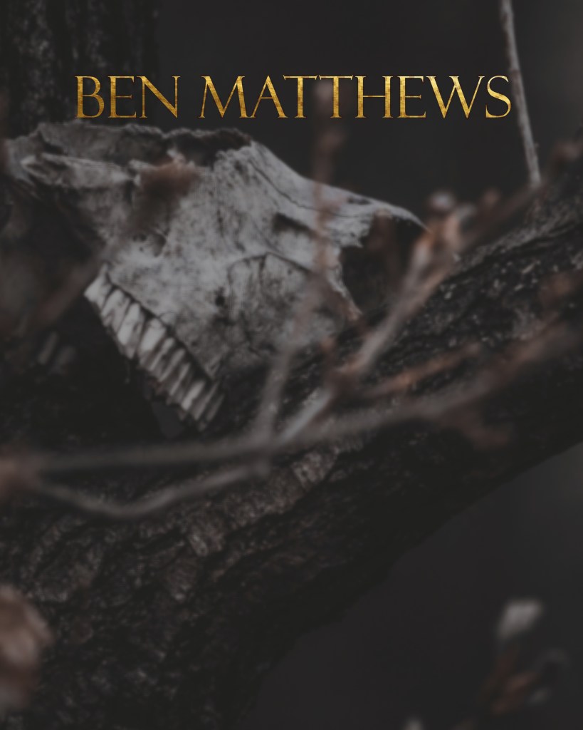 A close-up of a skull resting on a tree branch with dark, blurred background and the text 'BEN MATTHEWS' in gold at the top.